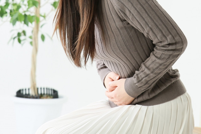 お腹を押さえる女性の写真